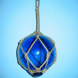 May include: A blue glass buoy with a rope net, hanging from a hook.