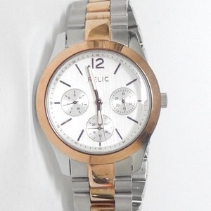 May include: A silver and rose gold tone watch with a white face and three subdials. The watch has a stainless steel band.