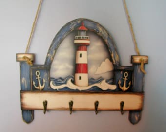 Könnte beinhalten: Wand-Schlüsselhalter aus Holz mit maritimem Thema. Verfügt über ein Leuchtturm-Design mit roten und weißen Streifen, blauen Akzenten und Ankerdetails. Enthält vier Haken für Schlüssel und ein Seil zum Aufhängen.