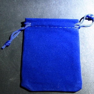 Puede incluir: Una bolsa de terciopelo azul real con cord&oacute;n. La bolsa es rectangular con la parte inferior redondeada y una costura en la parte superior. Un cord&oacute;n azul a juego se enhebra y se ata para cerrar la bolsa.