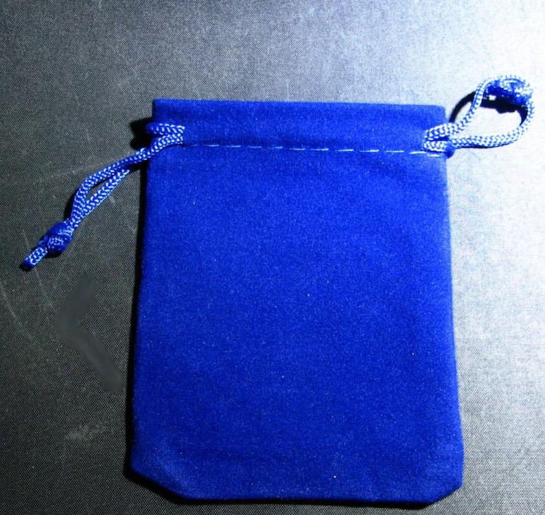 Puede incluir: Una bolsa de terciopelo azul real con cord&oacute;n. La bolsa es rectangular con la parte inferior redondeada y una costura en la parte superior. Un cord&oacute;n azul a juego se enhebra y se ata para cerrar la bolsa.