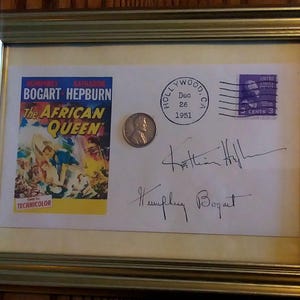 Peut inclure: Un cadre contenant un autographe de Humphrey Bogart et Katharine Hepburn du film "La Reine d'Afrique". L'autographe est sur une enveloppe vintage avec un timbre de 3 cents datant de 1951. Une pièce d'argent est également incluse dans le cadre.