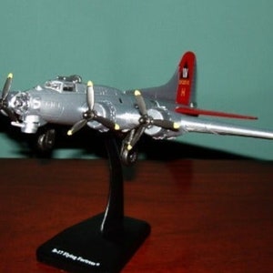 May include: A silver model aeroplane with red accents. The plane has four propellers and is on a black stand. The plane has the text "IV" and "MISSOURI" on the tail.