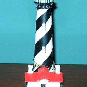 May include: A black and white striped lighthouse figurine with a red roof and a base that reads "ST. AUGUSTINE, FL".