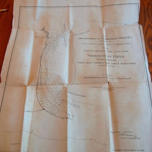 May include: A black and white map of the Shrewsbury River in New Jersey, showing the improvement of the river after dredging. The map includes the North Branch and Junction, the Cross-Over Channel, and Lower Rocky Point. The map is dated 1893 and is respectfully submitted by Capt. Thos. L. Casey, Corps of Engineers, USA.