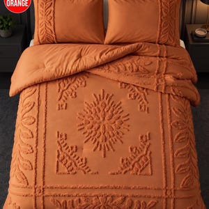 May include: A burnt orange comforter set featuring a textured, tufted leaf and floral pattern. The bedding includes two matching pillow shams with side-panel detailing and a central tufted design on the comforter, all in a solid burnt orange colour.