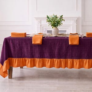 May include: A rectangular purple tablecloth with a solid orange ruffled border. The table is set with a beige runner, orange napkins, and a vase of greenery. The text "PATTERN-06" is visible in the bottom left corner of the image.