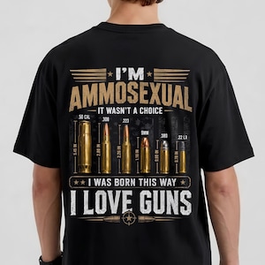 Può includere: Una t-shirt nera con una grafica sul retro che riporta il testo I'M AMMOSEXUAL IT WASN'T A CHOICE I WAS BORN THIS WAY I LOVE GUNS. Il design include illustrazioni di sei diversi bossoli di proiettile etichettati con i relativi calibri.