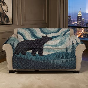 以下が含まれることがあります： 黒いクマのデザインのソファカバー。カバーは、下部に森のシーンがある青と白の波模様です。クマは濃い色で、右方向に歩いています。