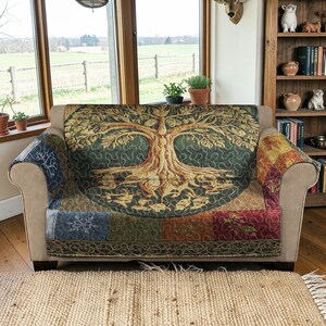 Peut inclure: Un canapé beige avec une tapisserie décorative représentant l'arbre de vie drapée sur le dossier. La tapisserie présente un motif d'arbre détaillé dans les tons marron et vert, avec un motif patchwork sur la partie inférieure.