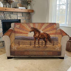 以下が含まれることがあります： 夕焼けを背景に、柵のある野原に立つ茶色の馬が描かれたソファカバー。素朴なテーマのキルトデザイン。カラーパレットには、茶色、オレンジ、タンの色合いが含まれています。