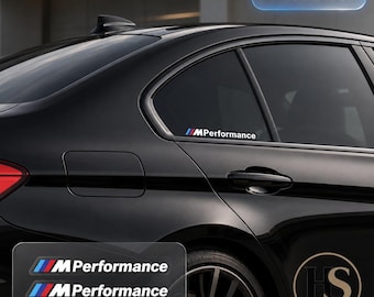 Puede incluir: Dos pegatinas M Performance con las icónicas franjas inclinadas en azul, morado y rojo seguidas del texto blanco MPerformance. Los adhesivos se muestran aplicados en la ventanilla lateral trasera de un coche negro, con la etiqueta 2X PIECES.