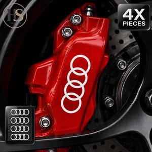 Könnte beinhalten: Ein leuchtend roter Bremssattel mit einem weißen Audi-Logo-Aufkleber bestehend aus vier Ringen. Das Bild enthält einen kleinen rechteckigen Einsatz, der vier identische weiße Ring-Aufkleber und den Text 4X PIECES zeigt.