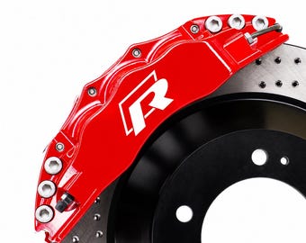 Puede incluir: Una pinza de freno de automóvil de color rojo brillante con un logotipo R blanco, montada sobre un disco de freno metálico circular negro y plateado con una serie de pequeños orificios de ventilación espaciados uniformemente y pernos plateados.