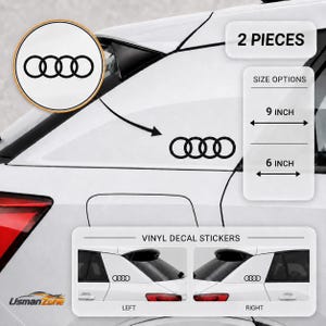 Può includere: Un set di due adesivi in vinile nero con il logo Audi a quattro anelli. Gli adesivi sono mostrati applicati sul finestrino laterale posteriore di un veicolo bianco. Il testo sull'immagine indica opzioni di dimensioni di 22,86 cm e 15,24 cm.
