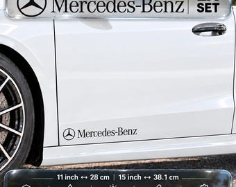 Puede incluir: Un juego de dos calcomanías de vinilo negro de Mercedes-Benz aplicadas en el panel lateral inferior de un automóvil blanco. Las calcomanías muestran el logotipo y el texto de Mercedes-Benz. El juego incluye dos opciones de longitud: 28 cm y 38,1 cm.