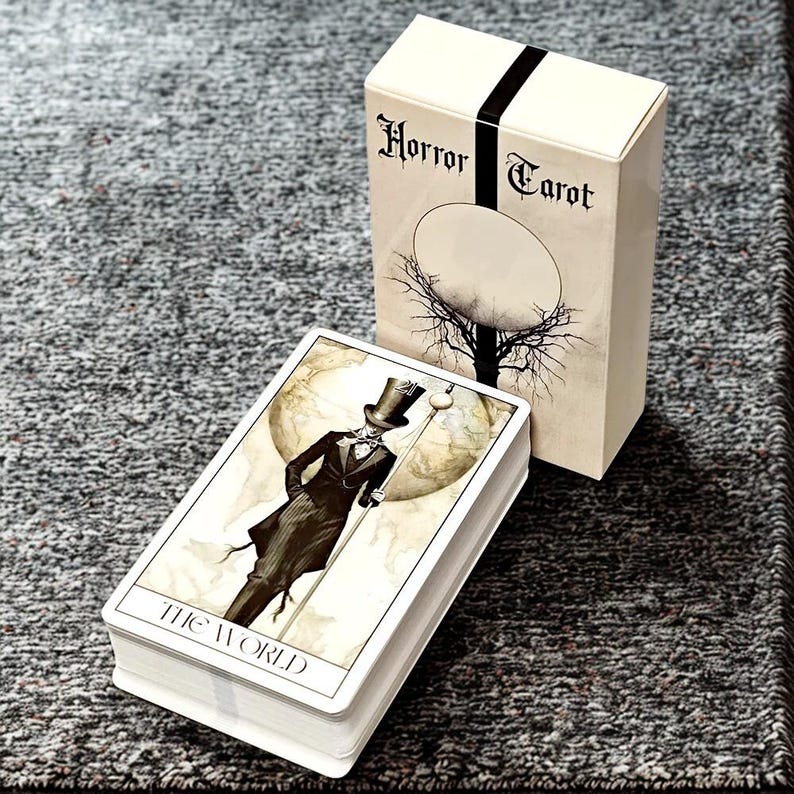 Peut inclure: Un jeu de cartes "Horror Tarot" avec une bo&icirc;te assortie. Les cartes pr&eacute;sentent des illustrations d'une figure en haut-de-forme et en costume. La bo&icirc;te porte l'inscription "Horror Tarot" avec une bande noire.
