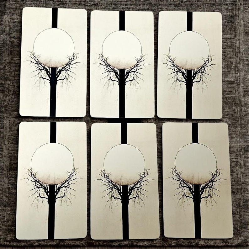 Peut inclure: Six cartes de tarot rectangulaires au design minimaliste. Chaque carte pr&eacute;sente une bande verticale noire, un cercle blanc et une silhouette d'arbre noire. Les cartes sont dispos&eacute;es sur une surface textur&eacute;e de couleur neutre.