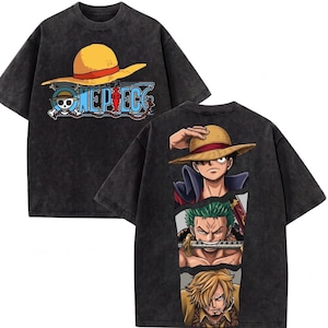 Könnte beinhalten: Dunkelgraues T-Shirt mit gelbem Strohhut und dem Text "ONE PIECE" mit Totenkopf und gekreuzten Knochen. Auf der Rückseite des Shirts sind drei Anime-Charaktere abgebildet. Ein stilvolles Grafik-T-Shirt.