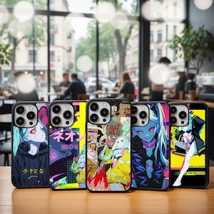 Puede incluir: Cinco fundas para teléfono con ilustraciones de estilo anime en varios colores. Cada funda tiene un diseño diferente, con personajes con detalles en azul, rosa y amarillo. Las fundas se exhiben sobre una superficie de madera.
