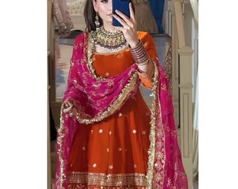 Könnte beinhalten: Ein orangefarbenes und pinkfarbenes Salwar-Kameez-Set mit aufwendiger Goldstickerei und Verzierungen. Ein passendes pinkfarbenes Dupatta mit goldenem Besatz drapiert über den Schultern. Der Text "LOOMLAGACY" ist sichtbar.