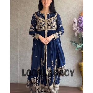 May include: A navy blue embroidered dress with gold accents. The dress features intricate gold embroidery on the bodice, sleeves, and hem. The text "LOOK LEGACY" is visible on the bottom of the dress. The dress is floor-length.
