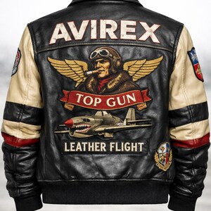 May include: A black leather flight jacket with cream-colored sleeves featuring red accents. The back displays an embroidered pilot with wings, the text AVIREX, TOP GUN, and LEATHER FLIGHT, along with a fighter plane graphic and various circular patches.