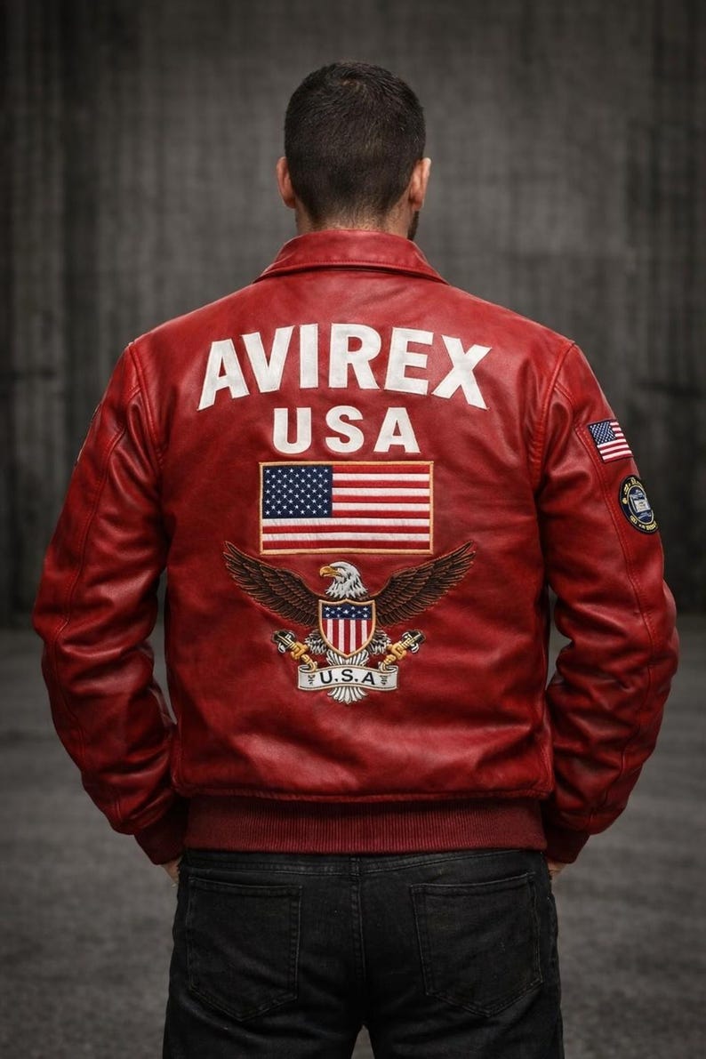 May include: A red leather jacket featuring the white text AVIREX USA on the back, a large embroidered American flag, and a bald eagle emblem with the text U.S.A. below it. The sleeves include a small American flag patch and a circular logo patch.