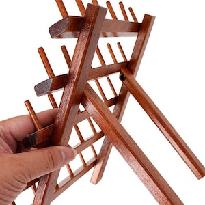 May include: A wooden thread spool holder with a rich, dark brown finish. The rack is designed with multiple pegs to hold spools of thread, and it has a foldable design for easy storage. The holder is made of wood and has a glossy finish.
