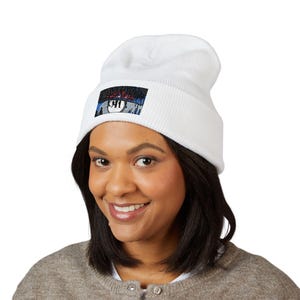 May include: A white beanie hat with a rectangular patch. The patch displays the text "Lost River" above a graphic of a pool ball with the number "911". The hat is made of a knitted material.