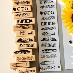 May include: A collection of wooden stamps with various black and white designs, including fruits, flowers, and decorative borders. A bouquet of bright yellow sunflowers with brown centers is also present.