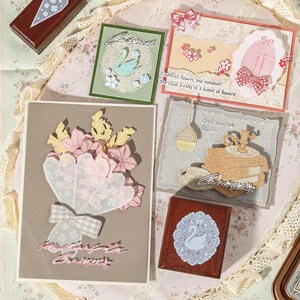 May include: A collection of handmade greeting cards and wooden stamps featuring lace textures, floral motifs, and swan illustrations. The cards include text such as Countless flowers and romance, The ritual feeling of a bunch of flowers, and Grow your own flowers.