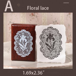 May include: A rectangular wooden stamp with a floral lace pattern in white, accompanied by a white paper swatch showing the same floral lace design stamped in black ink. The stamp measures 1.69 by 2.36 inches as indicated by the text.