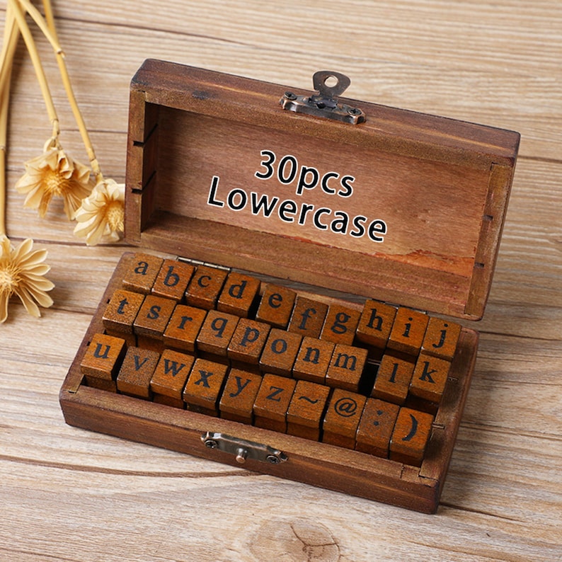 May include: A wooden box containing 30 lowercase letter stamps. The box is open, revealing the neatly arranged stamps. The text "30pcs Lowercase" is printed on the inside of the box. The stamps are made of wood with black ink letters.