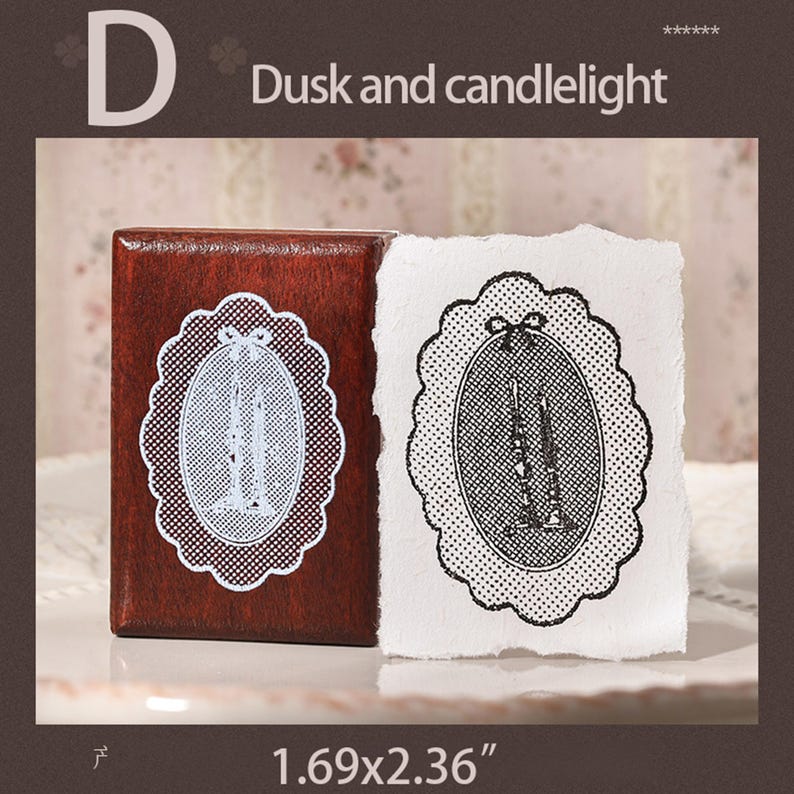 May include: A rectangular wooden stamp with a dark brown finish featuring a scalloped oval design of two candles. Next to the stamp is a white paper impression showing the same black ink design. The stamp measures 1.69 by 2.36 inches.