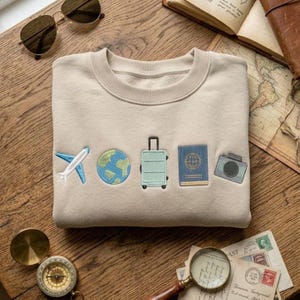 May include: A white ceramic mug with a black handle and the text "But First, Coffee" in a bold, black font. The mug is set against a blurred background, suggesting a cozy setting.