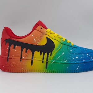 Pode incluir: Um t&ecirc;nis Air Force 1 personalizado com um gradiente de arco-&iacute;ris. O t&ecirc;nis transita do vermelho para o azul, com pingos pretos e respingos brancos. O swoosh da Nike &eacute; preto e os cadar&ccedil;os s&atilde;o amarelos. A sola &eacute; de cor s&oacute;lida.