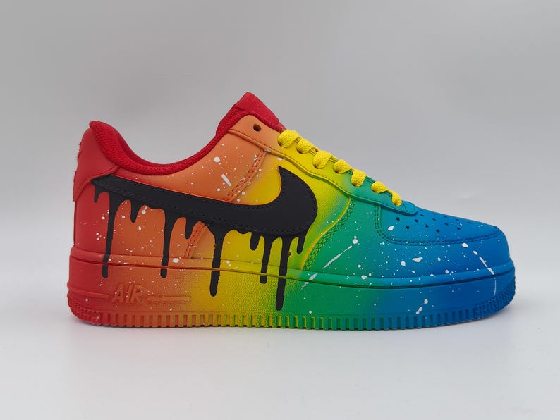 Pode incluir: Um t&ecirc;nis Air Force 1 personalizado com um gradiente de arco-&iacute;ris. O t&ecirc;nis transita do vermelho para o azul, com pingos pretos e respingos brancos. O swoosh da Nike &eacute; preto e os cadar&ccedil;os s&atilde;o amarelos. A sola &eacute; de cor s&oacute;lida.