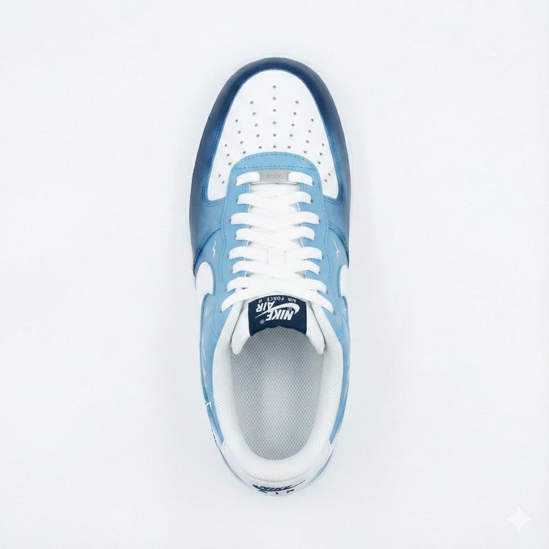 Puede incluir: Vista superior de una zapatilla Nike Air Force 1 azul claro y blanca. La zapatilla presenta una puntera blanca con peque&ntilde;as perforaciones, cordones blancos y un logotipo de Nike azul marino en la leng&uuml;eta. Los laterales y el tal&oacute;n son de color azul claro con detalles blancos.