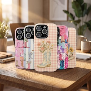 May include: A collection of phone cases with various designs, including cowboy boots, floral patterns, and gingham backgrounds. The cases are arranged on a wooden surface, showcasing a range of colors and styles. The cases are designed for a smartphone.