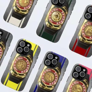 May include: A collection of phone cases featuring a gold Power Rangers emblem on a black band. Each case has a different colored stripe, including yellow, blue, red, green, and white, with the words "POWER RANGERS" around the emblem.