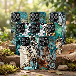 May include: A collection of phone cases with various animal print and floral designs. The cases feature patterns such as zebra stripes, leopard spots, and tiger illustrations, with teal and brown accents. The cases are displayed on a wooden surface.