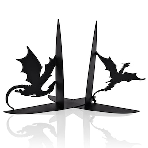 May include: Black metal bookends featuring dragon silhouettes. The bookends have a minimalist design with two vertical supports and a base that intersects to form an X shape. The dragons are depicted in flight, adding a fantasy element to the functional decor.