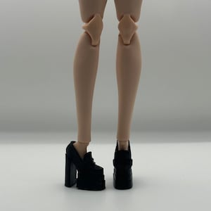 May include: Black platform heels with thick block heels. The shoes have a square toe and a strap across the top of the foot. The heels are approximately 4 inches high.