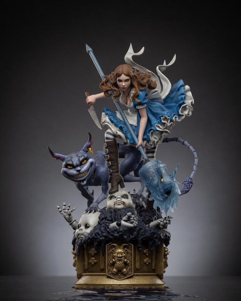 May include: A detailed figurine featuring a brown-haired character in a blue dress and white apron, holding a knife and a long staff. Beside them is a grinning purple cat-like creature, all standing atop a base of doll heads and a gold emblem.