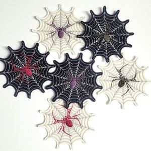 Könnte beinhalten: Sechs spinnennetzförmige Aufnäher mit Spinnenmuster. Die Spinnen und Netze sind in verschiedenen Farben, darunter Schwarz, Weiß, Rot und Lila. Diese Aufnäher sind wahrscheinlich für Halloween. Die Aufnäher sind kreisförmig.