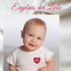 Könnte beinhalten: Ein weißer kurzärmeliger Babybody mit einem kleinen roten Herzaufnäher auf der Brust, der die weiß gestickten Buchstaben N&L trägt. Über dem Baby steht der Text "Ergebnis der Liebe" in einer roten Schreibschrift auf strukturiertem Grund.