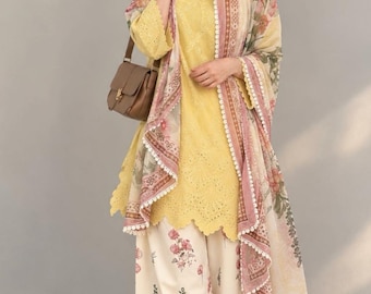 May include: A bright yellow tunic with intricate eyelet embroidery and a scalloped hem, paired with cream-colored wide-leg trousers featuring a pink and green floral print, and a matching floral dupatta with a delicate white lace trim.