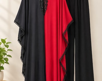 May include: A two-piece outfit consisting of a black and red color-blocked kaftan tunic and matching black wide-leg trousers. The kaftan features a V-neckline with black lace trim, sequin embellishments, and black pom-pom fringe along the hem.