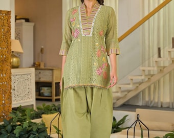May include: A light olive green tunic featuring intricate eyelet embroidery, a V-neckline with a multi-colored striped border, and floral embroidery on the chest. The tunic is paired with matching olive green wide-leg trousers with a pleated design.